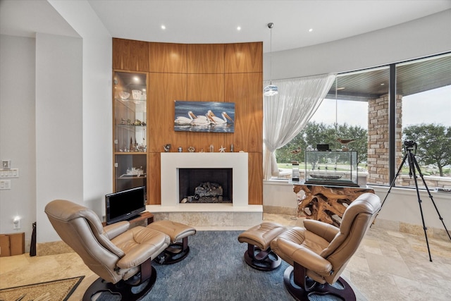 living area with recessed lighting, a large fireplace, and stone finish floor