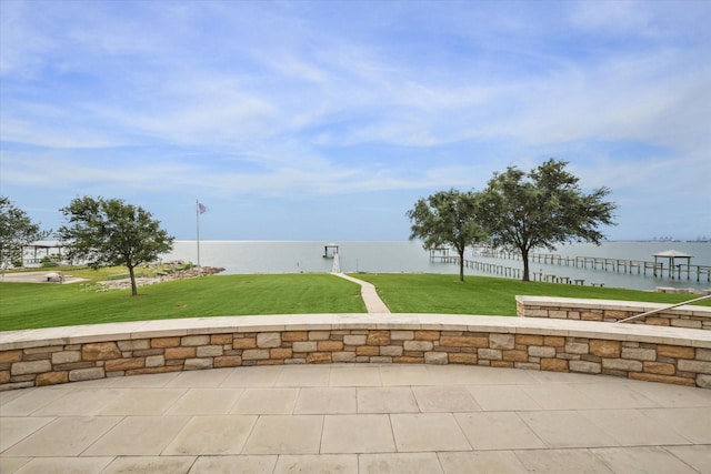 view of property's community with a water view, a lawn, and a patio