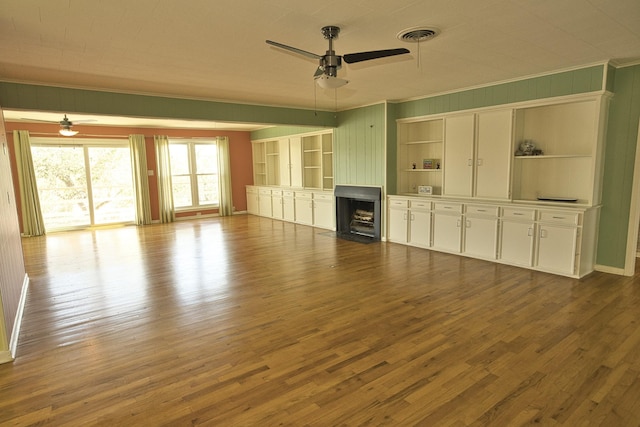 unfurnished living room with ceiling fan, crown molding, dark wood-style flooring, and a fireplace with flush hearth