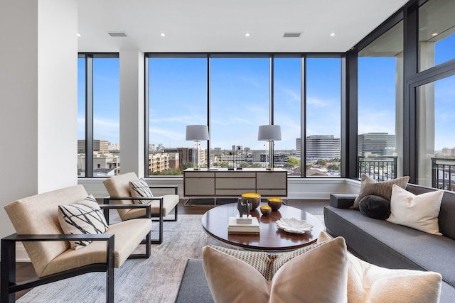 living room featuring a view of city, a wealth of natural light, wood finished floors, and visible vents