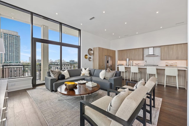 living room with recessed lighting, a high ceiling, dark wood-style flooring, visible vents, and a view of city