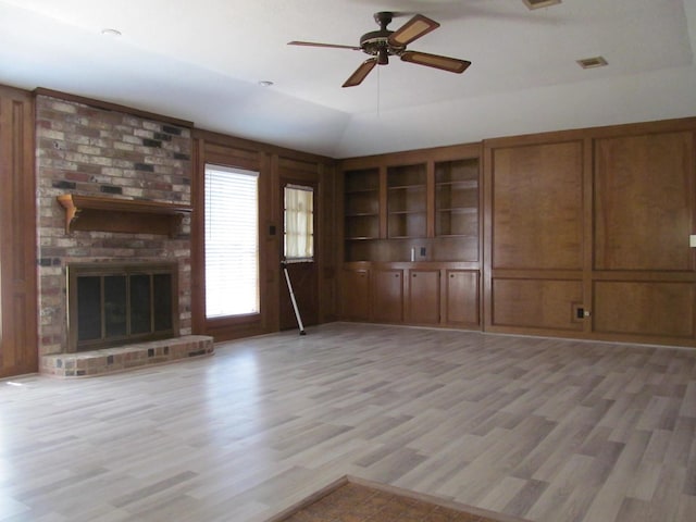 unfurnished living room featuring visible vents, light wood-style floors, lofted ceiling, ceiling fan, and a brick fireplace