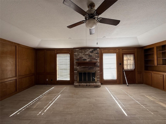 unfurnished living room with lofted ceiling, a decorative wall, a fireplace, and a healthy amount of sunlight