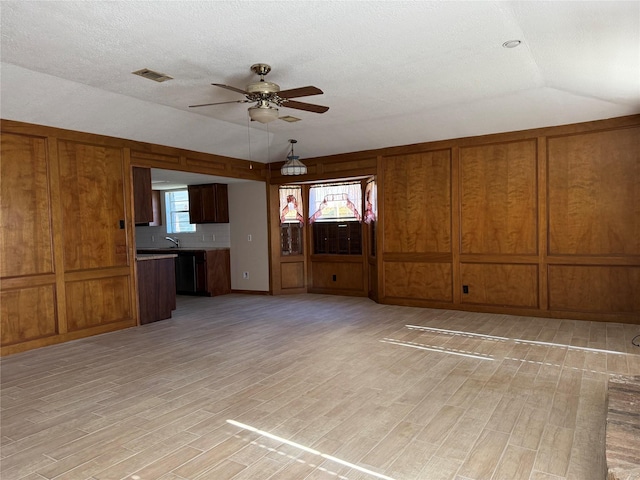 unfurnished living room with lofted ceiling, visible vents, light wood-type flooring, and a ceiling fan