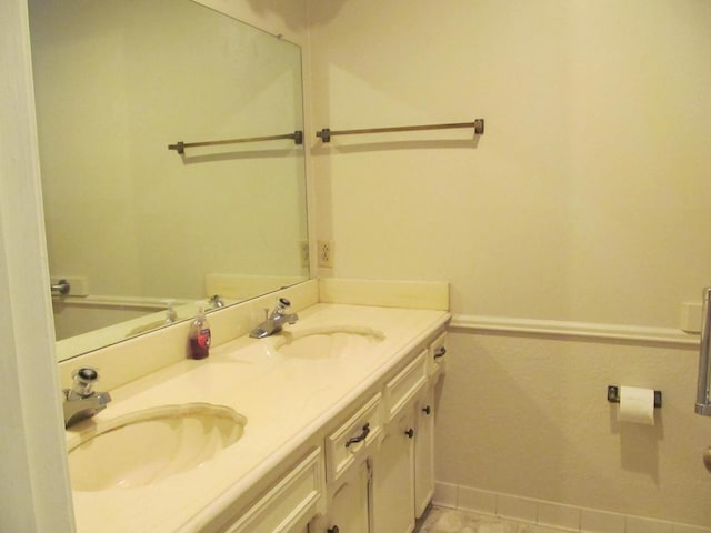 full bath with double vanity, a sink, and baseboards