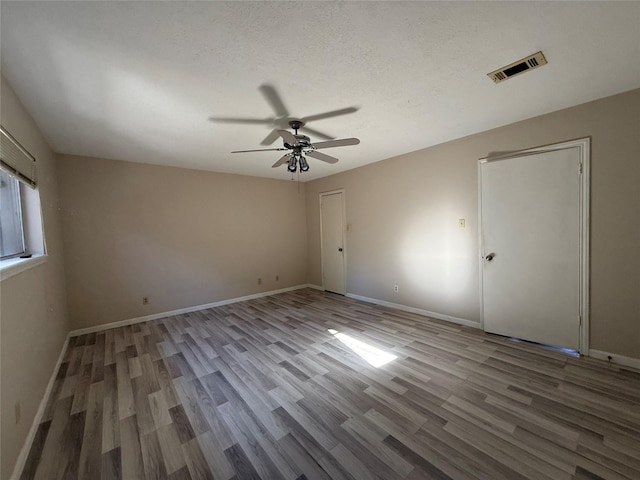 unfurnished bedroom with visible vents, a textured ceiling, baseboards, and wood finished floors