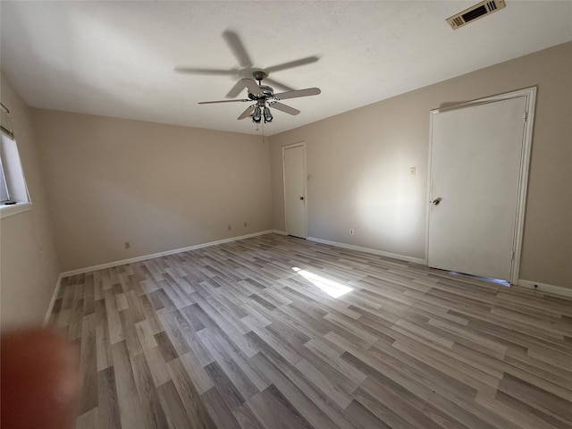 unfurnished room with visible vents, ceiling fan, baseboards, and wood finished floors