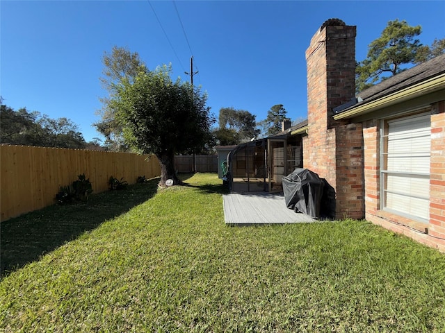 view of yard featuring a sunroom, a fenced backyard, and a wooden deck