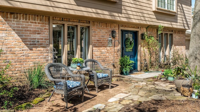 property entrance featuring a patio area and brick siding