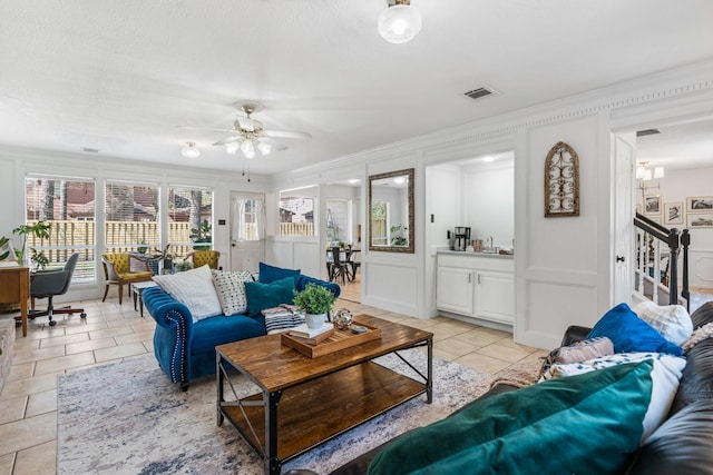 living area with light tile patterned floors, stairs, visible vents, and a decorative wall