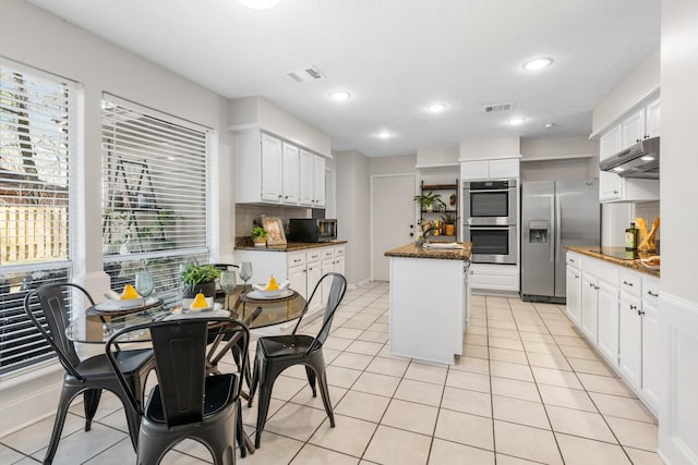 kitchen with appliances with stainless steel finishes, backsplash, visible vents, and under cabinet range hood