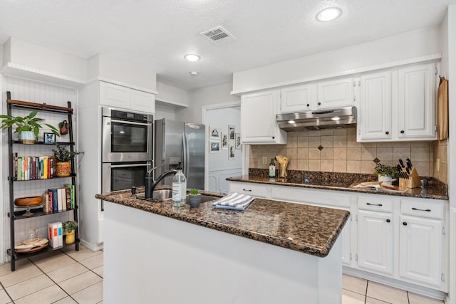 kitchen with stainless steel appliances, visible vents, under cabinet range hood, and light tile patterned floors