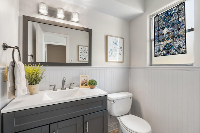 bathroom with a wainscoted wall, vanity, and toilet