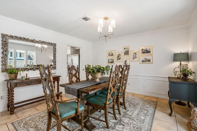 dining room featuring a chandelier, light tile patterned floors, visible vents, ornamental molding, and wainscoting