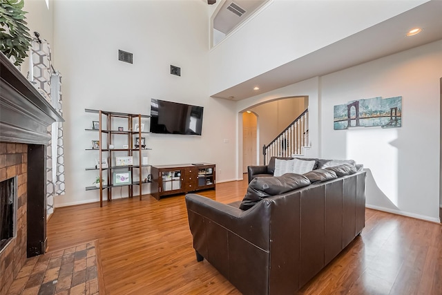 living area with visible vents, arched walkways, wood finished floors, and a tiled fireplace