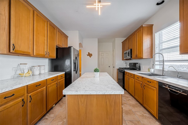 kitchen with a sink, black appliances, light countertops, and a center island