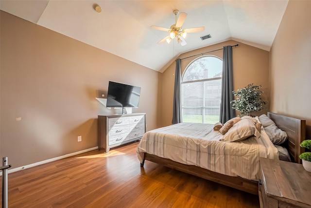 bedroom featuring visible vents, baseboards, vaulted ceiling, wood finished floors, and a ceiling fan