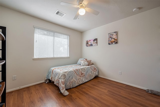 bedroom with visible vents, baseboards, and wood finished floors