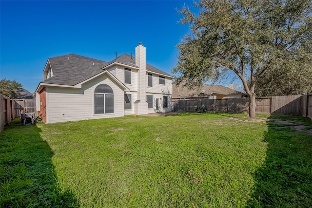 back of house with a yard, a fenced backyard, and a chimney