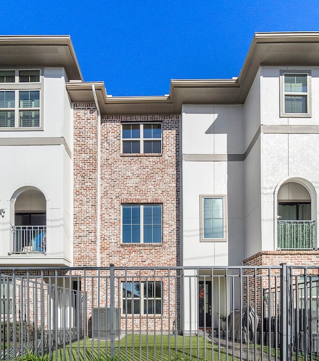 exterior space with brick siding, stucco siding, and fence