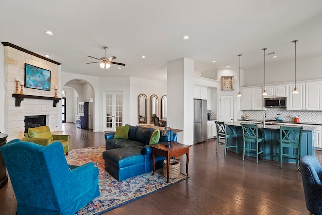 living area featuring ceiling fan, a stone fireplace, recessed lighting, dark wood-type flooring, and french doors