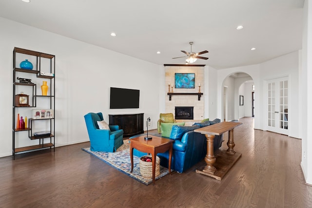 living room featuring arched walkways, a fireplace, wood finished floors, and recessed lighting