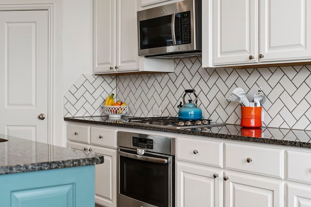 kitchen with tasteful backsplash, white cabinetry, appliances with stainless steel finishes, and dark stone counters