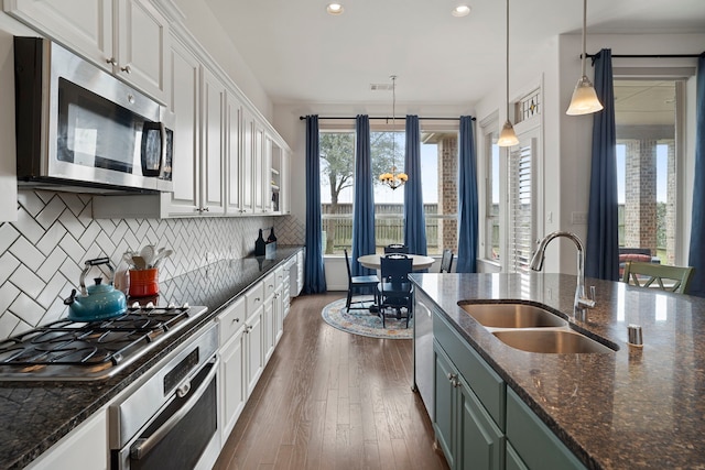 kitchen with decorative backsplash, appliances with stainless steel finishes, dark wood-style flooring, white cabinetry, and a sink