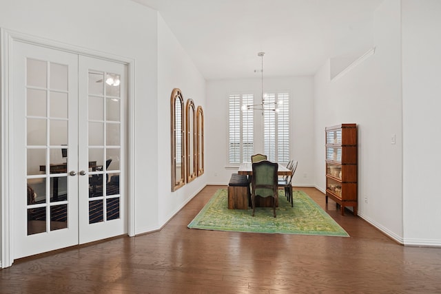 unfurnished dining area featuring an inviting chandelier, baseboards, wood finished floors, and french doors