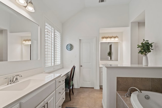 bathroom featuring lofted ceiling, tiled tub, tile patterned flooring, and vanity