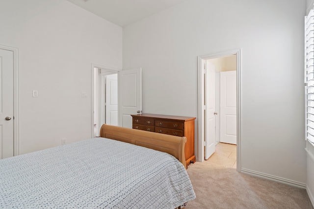 bedroom featuring baseboards, high vaulted ceiling, and light colored carpet