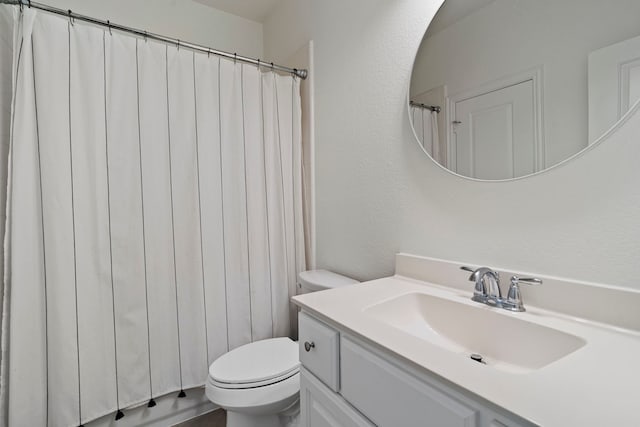 bathroom with a textured wall, vanity, and toilet