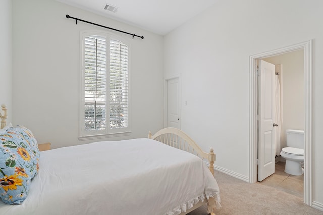 carpeted bedroom with tile patterned flooring, ensuite bath, visible vents, and baseboards