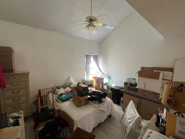 bedroom with lofted ceiling, ceiling fan, and a textured ceiling