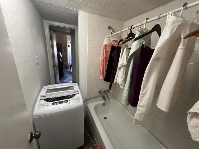 bathroom featuring toilet, shower / bath combo with shower curtain, and a textured ceiling