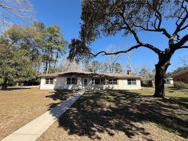 ranch-style house featuring a chimney and a front lawn