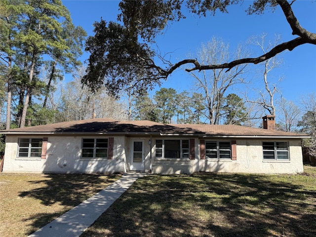 single story home featuring stucco siding, a chimney, and a front yard