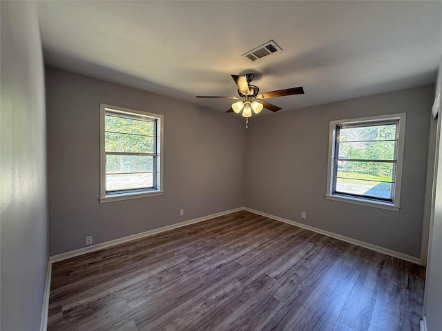 spare room with dark wood-style floors, ceiling fan, visible vents, and baseboards