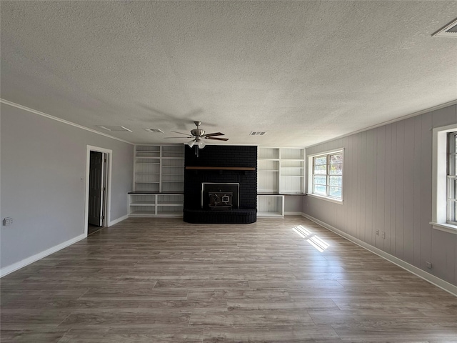 unfurnished living room with built in features, visible vents, ceiling fan, a textured ceiling, and wood finished floors