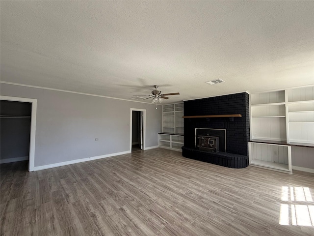 unfurnished living room featuring a fireplace, a textured ceiling, baseboards, and wood finished floors