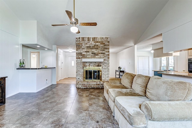 living room featuring lofted ceiling, a brick fireplace, ceiling fan, tile patterned flooring, and baseboards