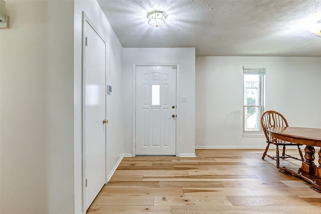 entrance foyer with a textured ceiling, light wood finished floors, and baseboards