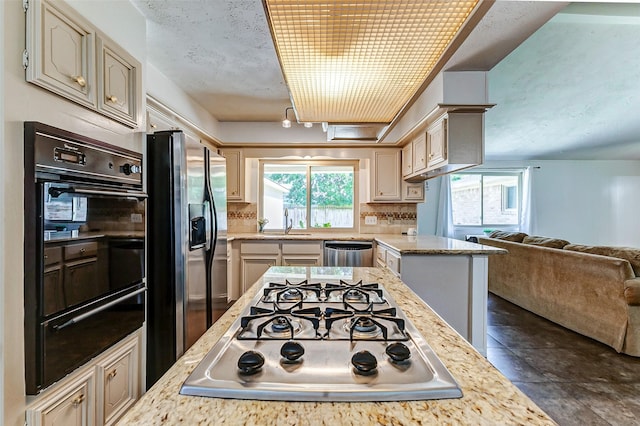 kitchen featuring stainless steel appliances, a sink, open floor plan, backsplash, and a warming drawer