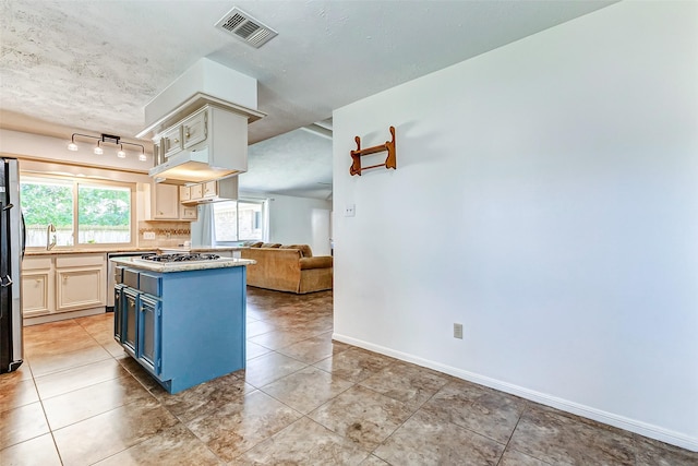 kitchen featuring baseboards, visible vents, open floor plan, freestanding refrigerator, and blue cabinets