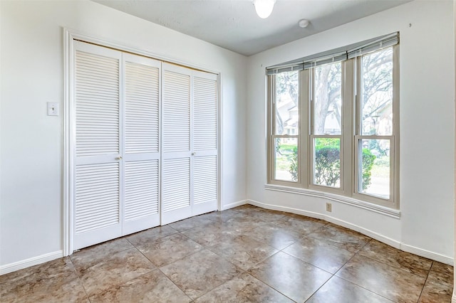 unfurnished bedroom featuring a closet, multiple windows, and baseboards