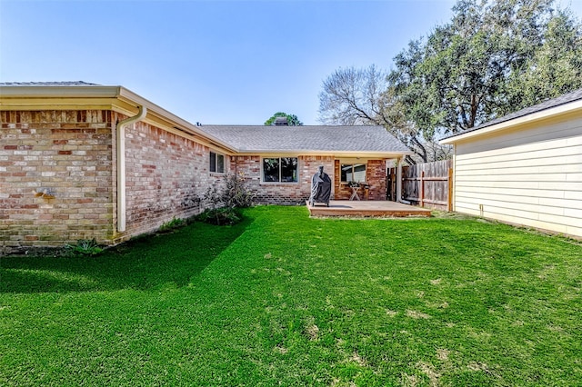 back of property featuring a patio area, fence, brick siding, and a lawn