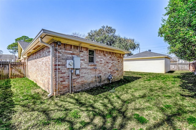 view of side of property with a yard, brick siding, and a fenced backyard