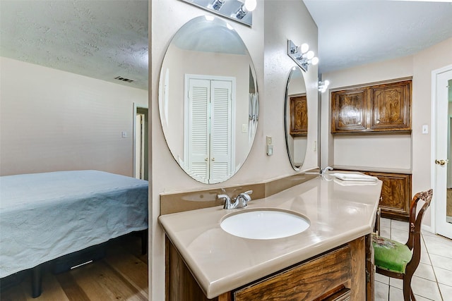 bathroom with tile patterned flooring, visible vents, a textured ceiling, and vanity