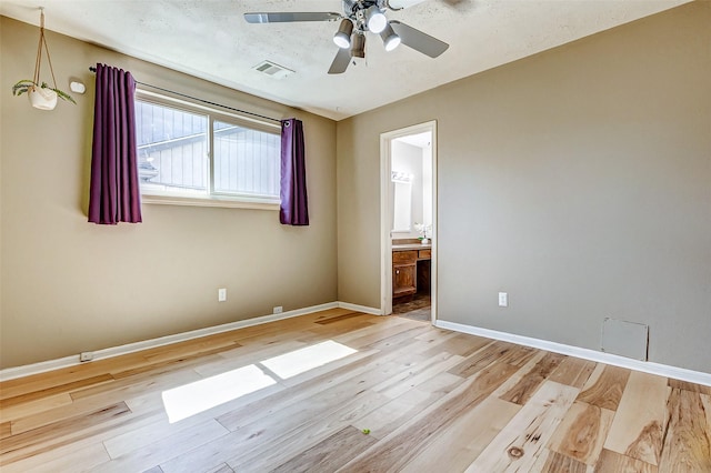 unfurnished bedroom with ensuite bathroom, a ceiling fan, baseboards, visible vents, and light wood-style floors