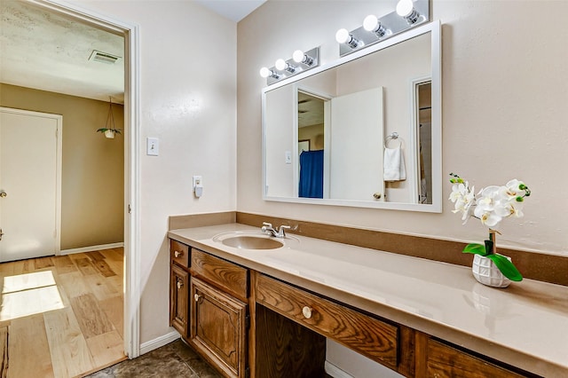 bathroom with baseboards, visible vents, wood finished floors, and vanity